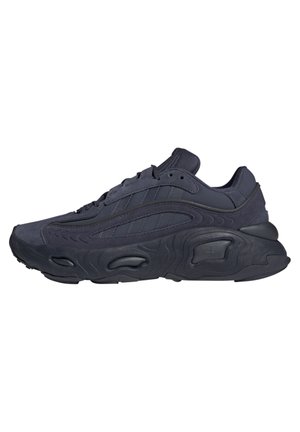 Czarny sportowy sneaker z teksturowaną podeszwą, cholewką z zamszu i tkaniny oraz wiązaniami, pokazany z boku na białym tle.