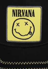 Black cap featuring a yellow rectangular patch with “NIRVANA” text and a black smiley face graphic, accented with zigzag stitching in yellow.