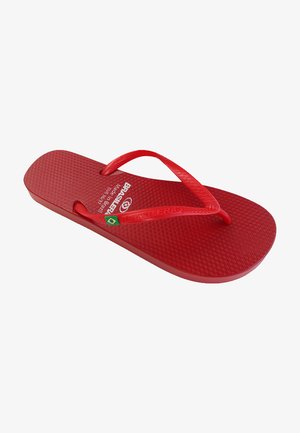 Chancla roja de goma. Presenta una plantilla texturizada y tiras delgadas. Incluye una marca y un pequeño logo en verde y amarillo.