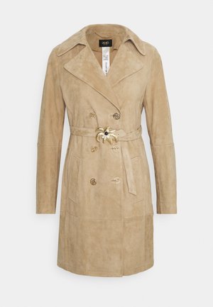 Manteau beige en daim à double boutonnage avec col large, boutons décoratifs dorés, ceinture avec boucle en forme de palmier et poches avant.