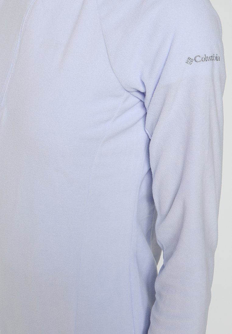 Sudadera de forro polar de color púrpura claro con cuello de media cremallera, textura suave y un logotipo en la manga izquierda, con un diseño ajustado.