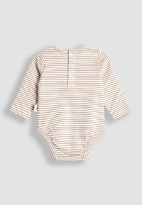 Babyheldragt med lange ærmer i beige og hvid striber med knapper på ryggen og mærkat på siden, lagt fladt på en lysegrå baggrund.