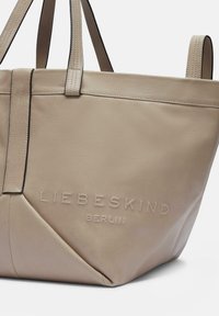 Beige Leder-Umhängetasche mit geprägtem "LIEBESKIND BERLIN"-Logo. Verfügt über zwei tonale Träger und eine strukturierte Form mit diagonalen Nähten.