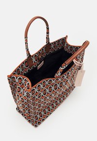 Tote bag met een geometrisch patroon in oranje, zwart en grijs op stof, bruine leren handvatten en een zwarte binnenkant. Inclusief een label.