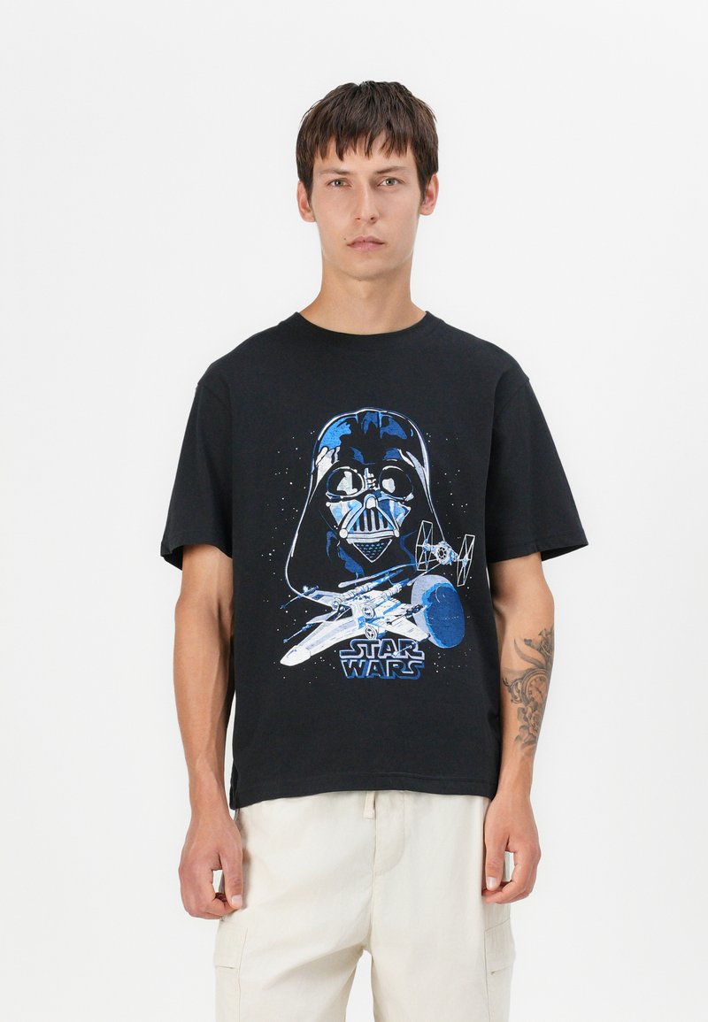 Svart bomull T-skjorte med et grafisk motiv av Darth Vader og et romskip, med blå detaljer. Korte ermer, avslappet passform, rund halslinning.