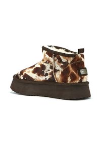 Smeđe i bijele čizme do članaka s uzorkom, izrađene od umjetnog krzna, s debelim smešnim đonom i tabom na peti koji prikazuje marku.