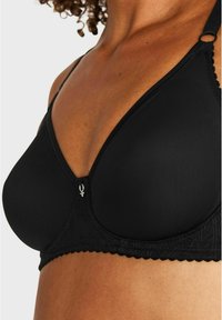 Svart vadderad bh med spetsdetaljer, v-ringning, justerbara axelband och silverfärgad detalj framme i mitten. Slät textur överlag.