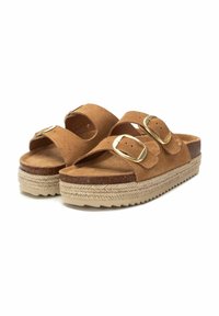 Sandalias de ante marrón con dos correas ajustables, hebillas de oro y una suela de plataforma que presenta yute trenzado y una base texturizada.