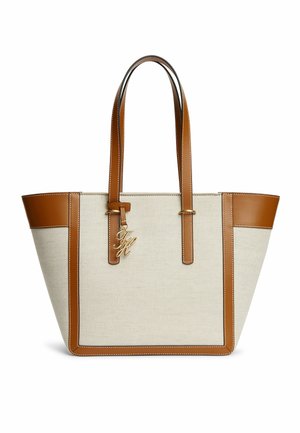 Sac cabas en toile beige avec garniture en cuir marron, doubles anses d'épaule et breloque dorée avec initiales suspendue près du haut.