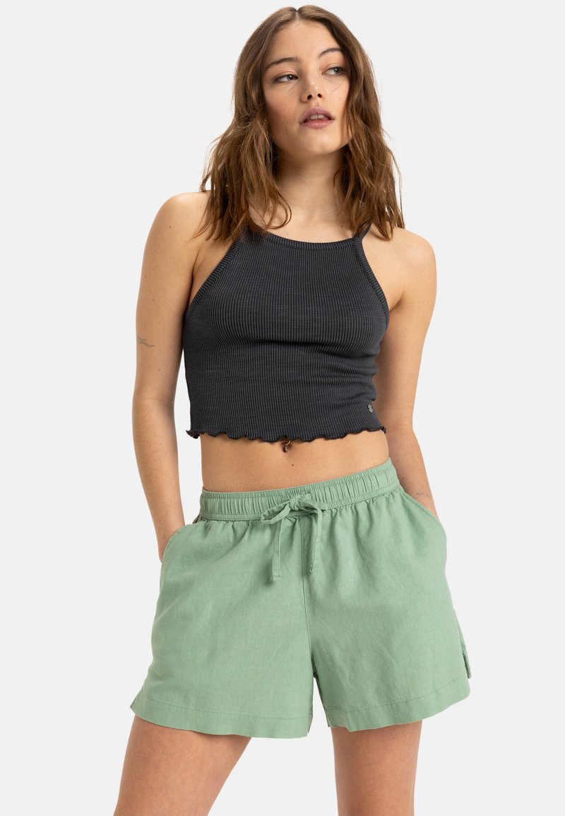 Czarny prążkowany crop top z falbany wzdłuż dolnej krawędzi, zestawiony z luźnymi, jasnooliwkowymi szortami z elastycznym paskiem w talii i bocznymi kieszeniami.