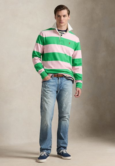 Πόλο με μακριά μανίκια σε ρίγες πράσινο και ροζ με λευκό γιακά, συνδυασμένο με ανοιχτό μπλε τζιν με φθορές και ναυτικά μπλε αθλητικά παπούτσια.