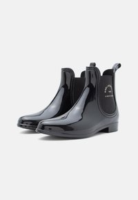 Botine negre impermeabile, cu un finisaj lucios, panouri laterale elastice și bucle pentru a le purta cu ușurință. Prezintă un toc mic tip block.