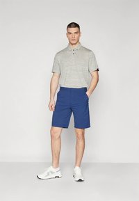 Gaiši pelēks svītrainais polo krekls ar īsām piedurknēm, kopā ar zilām šortiem. Apģērbs papildināts ar baltiem sporta apaviem.