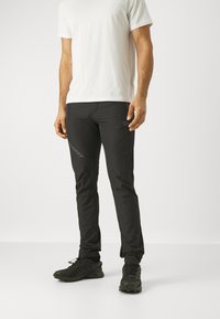 Zwarte sportbroek met een slim fit, gemaakt van lichtgewicht stof, met een subtiel logo en textuuraccenten aan de zijkanten.