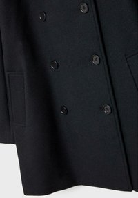 Manteau en laine noir à double boutonnage avec six boutons noirs et deux poches latérales, présenté en gros plan.