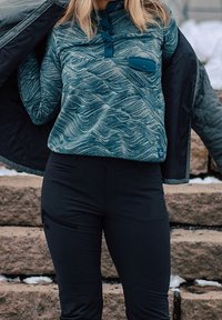 Langemouw teal patroon pullover met een kraag, knoopsluiting en een voorkantzak. Gepaard met zwarte broek met een zijzak met rits.