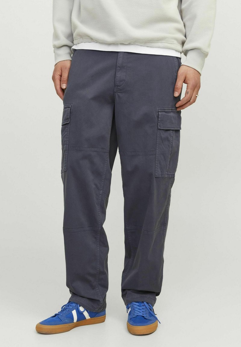 Mørkegrå cargo bukser med store sidelommer, lige ben-design og en slidstærk stofstruktur. Matchet med blå sneakers med hvide accenter.