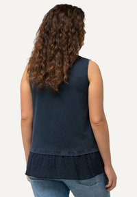 Top sin mangas de color azul marino con un dobladillo de encaje texturizado, confeccionado en tejido suave, con un diseño sencillo y un corte relajado.