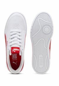 Baskets Puma blanches et rouges montrées en vue de dessus et sur la semelle, avec des lacets, des perforations, et le logo Puma sur la languette et la semelle.