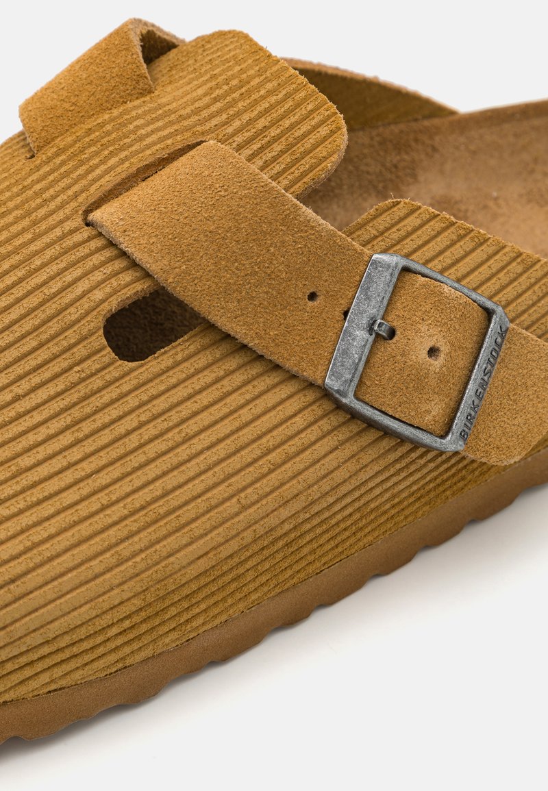 Braune Wildledersandale mit gerippter Textur, verstellbarem Schnallenverschluss und einem konturierten Fußbett mit flexiblem Fußbett.