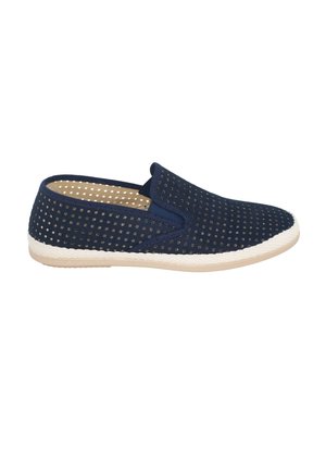 Zapato azul marino sin cordones con perforaciones cuadradas, suela blanca texturizada y diseño de perfil bajo sobre un fondo blanco.