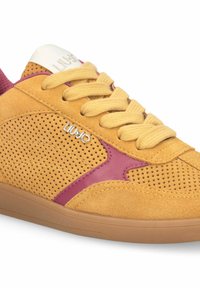 Baskets en daim jaune avec perforations, accents en cuir rouge, lacets jaunes, semelle gomme et logo argenté "LIUJO" sur le côté et la languette.