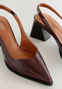 Bordo spicų nosių slingback kulniukų su tekstūruotu lakuotu paviršiumi, turinčių vidutinio aukščio blokinį kulniuką ir lygią smėlio spalvos vidpadį.