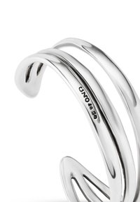 Bracelet jonc en ton argenté avec trois bandes lisses et courbées. Présente une finition polie et une marque gravée sur le côté intérieur.