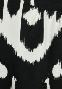 Black and white fabric featuring an abstract Ikat pattern with irregular, sharp edges, showcasing a matte texture and soft drape.