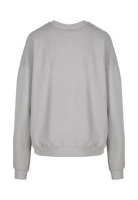 Sudadera gris claro con cuello redondo, hombros caídos y puños acanalados. Hecha de tela suave con un ajuste relajado y sin estampados visibles.