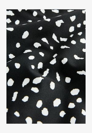 Zwarte stof met een ongelijkmatig wit stippenpatroon, met een gladde textuur en een lichte glans, die doet denken aan een zachte jersey-kwaliteit.