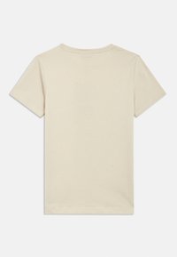 Īsroku krekls no gaiši bēša kokvilnas. Klasiska apaļa kakla līnija, standarta piegriezums, gluda tekstūra bez rakstiem vai rotājumiem.