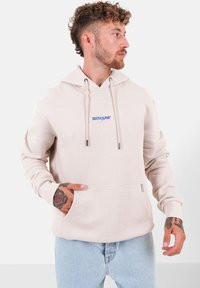 Felpa leggera beige chiaro in tessuto morbido con tasca a canguro, che presenta un piccolo logo blu sul petto e cordini.