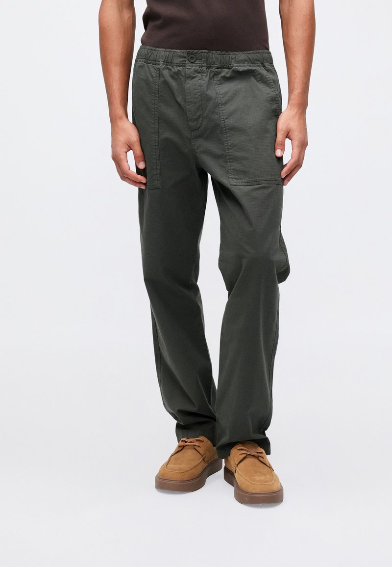 Σκούρο πράσινα, ελαφριά παντελόνια με ελαστική μέση και τσέπες cargo. Φτιαγμένα από λείο υλικό, με ίσια γραμμή κοπής.