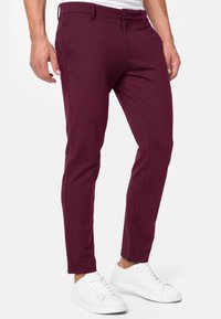 Bordeaux slim-fit broek van zachte stof, met een platte voorkant, riemlussen en zijzakken, gecombineerd met witte sneakers.