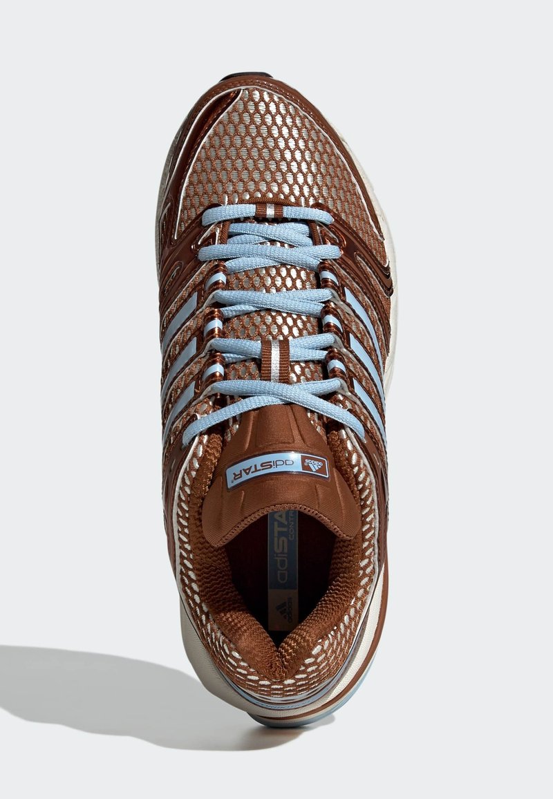 Chaussure de sport marron en mesh avec des lacets bleu clair, des accents métalliques et une surface texturée. Comprend une languette rembourrée et une semelle intérieure de marque.