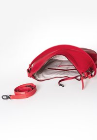 Rode leren handtas met een ritsopening, voorzien van een gemusterde binnenvoering en een verstelbare schouderband. Inclusief een afneembare schouderband.