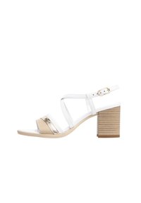 Sandale à talons blanche et beige avec des brides croisées, des accents métalliques et un talon bloc texturé. Équipée d'une sangle de cheville ajustable.