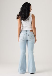 Hellblaue ausgestellte Jeans mit hoher Taille, ausgestattet mit Gesäßtaschen, einem Leder-Brandpatch und einer weichen Denim-Textur.