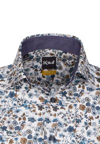 Camicia bianca con un motivo floreale in blu e marrone, caratterizzata da una vestibilità moderna, colletto scuro a contrasto e bottoni marroni.