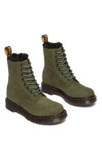 Groene suède veterschoenen met zwarte nepbont voering, gele en zwarte aantreklip en rubberen zool met contrasterende oranje stiksels.
