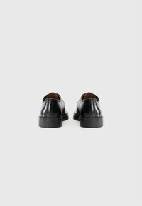 Black leather shoes with a smooth finish, rounded design, and low rubber soles, featuring a leather upper and minimal stitching details.