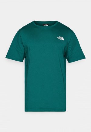 Camiseta de algodón en color verde azulado con cuello redondo y mangas cortas. Presenta un logotipo blanco en la parte superior izquierda del pecho y tiene una textura de tela suave.
