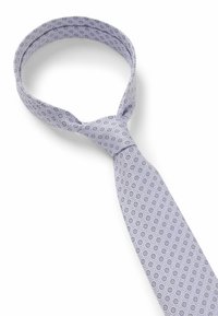 Cravate lilas claire ornée d'un motif circulaire en violet foncé et noir. Fabriquée en tissu lisse avec un design structuré et une extrémité pointue.