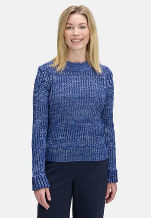 Blauwe gebreide trui met een gestructureerde stof, geribde halslijn en lange geribde manchetten. Draag het over een donkere broek.