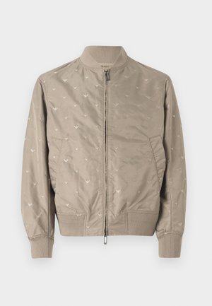 Vaalean beige bomber-takki pehmeällä pinnalla, jossa on hienovaraisia lintukuvioita, vetoketjukiinnitys, ribbireunat kauluksessa ja hihoissa. Kaksi sivutaskua.