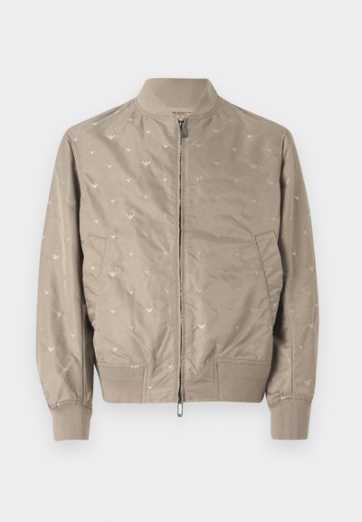 Svetlo bež bomberska jakna z mehko teksturo, ki se ponaša z diskretnimi vzorci ptic, zadrgo, rebrastim ovratnikom in manšetami. Dva stranska žepa.