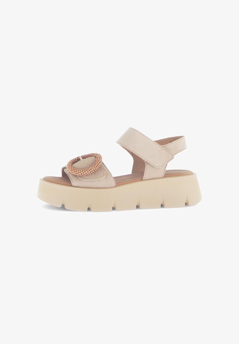 Beige platform sandaler med rund tå og en kraftig sål. Har en justerbar ankelrem og dekorative perler foran.