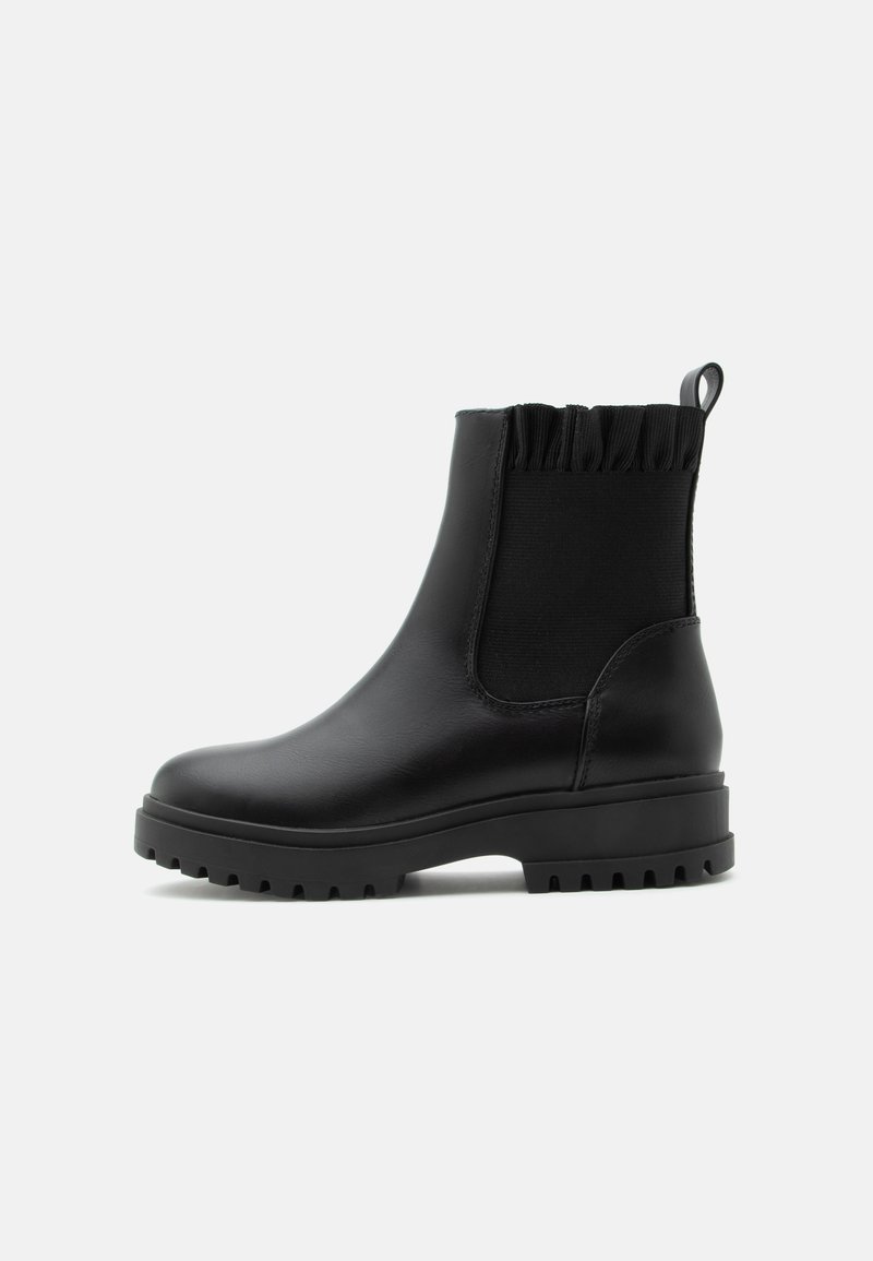 Bottine noire à talon épais, panneau latéral élastique, bord supérieur froncé et languette à tirer sur fond gris clair.