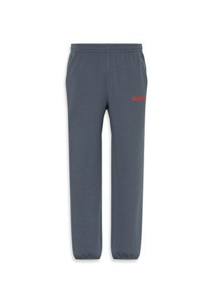 Pantaloni tuta grigi con elastico in vita e alle caviglie, caratterizzati da un tessuto testurizzato e dal logo rosso "CALVIN KLEIN" sulla coscia sinistra.